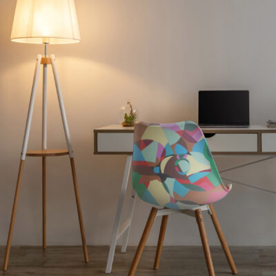 Vacant chair, laptop with empty screen on table, glowing lamp and potted plant on floor in evening on white wall background in office or living room. Modern minimalist interior, workplace, design ad