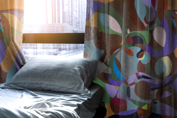 White comfort bed and soft pillow in modern bedroom. Bed near window and curtain at hotel in the morning with sunlight. Linen bed sheet and pillowcase. Bedroom interior design. Sleep with comfortable.